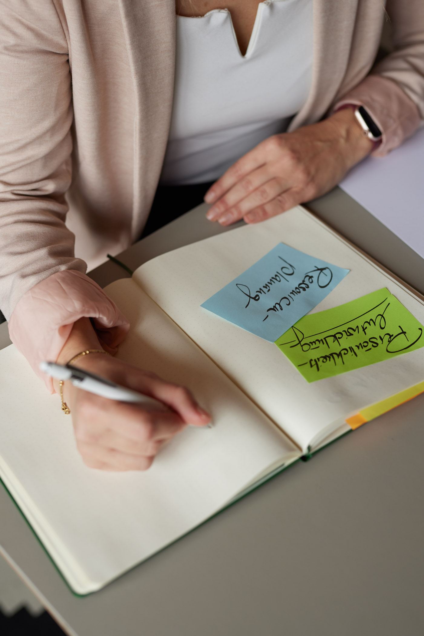 Offenes Notizbuch mit farbigen Post-its: Ressourcenplanung und persönliche Entwicklung im Coaching-Prozess