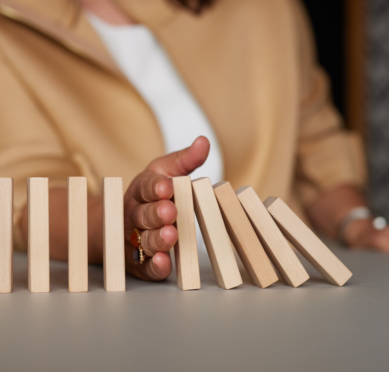 Hand stoppt fallende Dominosteine – Sinnbild für Krisenintervention, Verantwortung und Stabilisierung im Management
