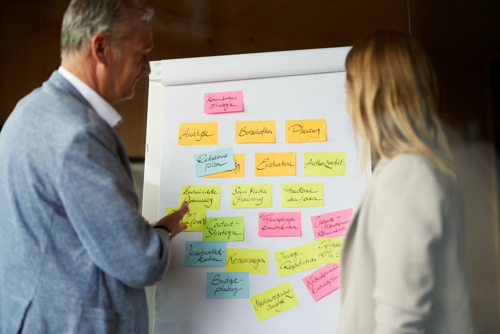 Zwei Personen stehen vor Flipchart mit bunten Notizzetteln – kreative Planung im Strategieprozess