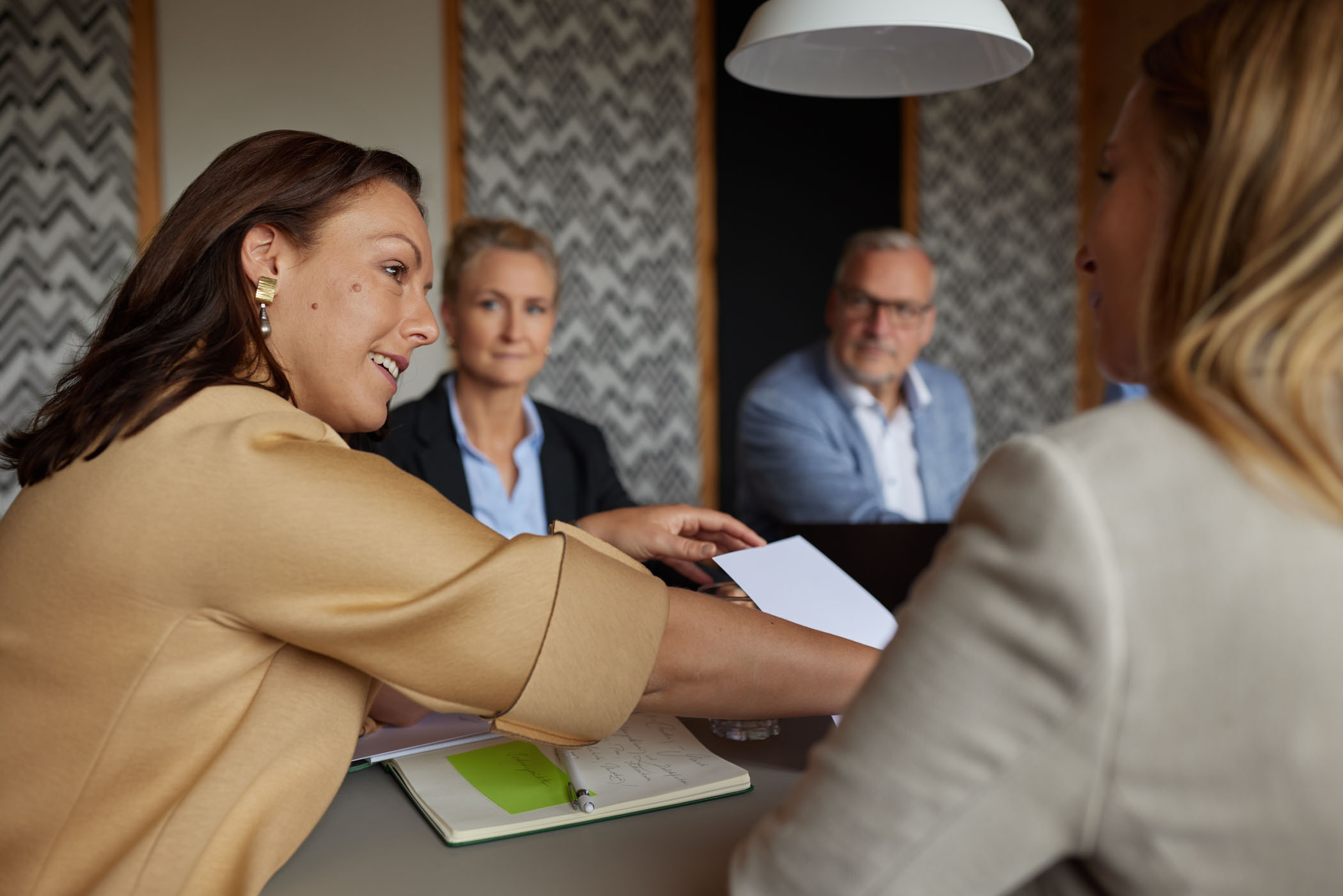 Frau mit Notizbuch spricht in kleiner Business-Runde über Konfliktgespräche – klare Kommunikation auf Augenhöhe