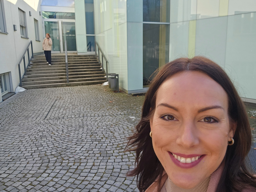 Franziska Zacher steht freundlich lächelnd vor dem Eingang des IFKW der LMU München